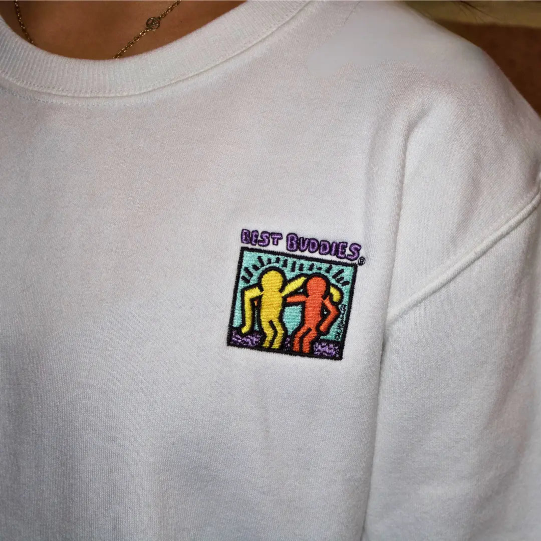 White crewneck sweatshirt with colorful Best Buddies Haring logo on the front
