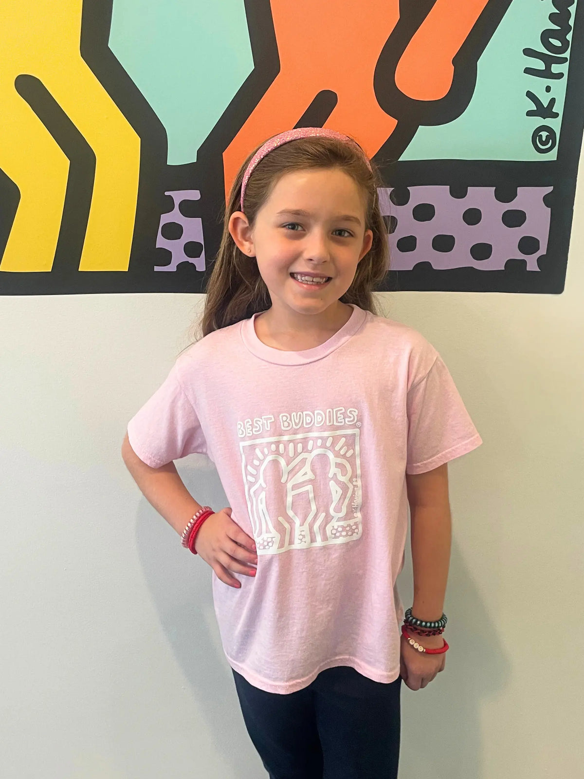 Pink youth shirt with White Haring Best Buddies Logo on the front