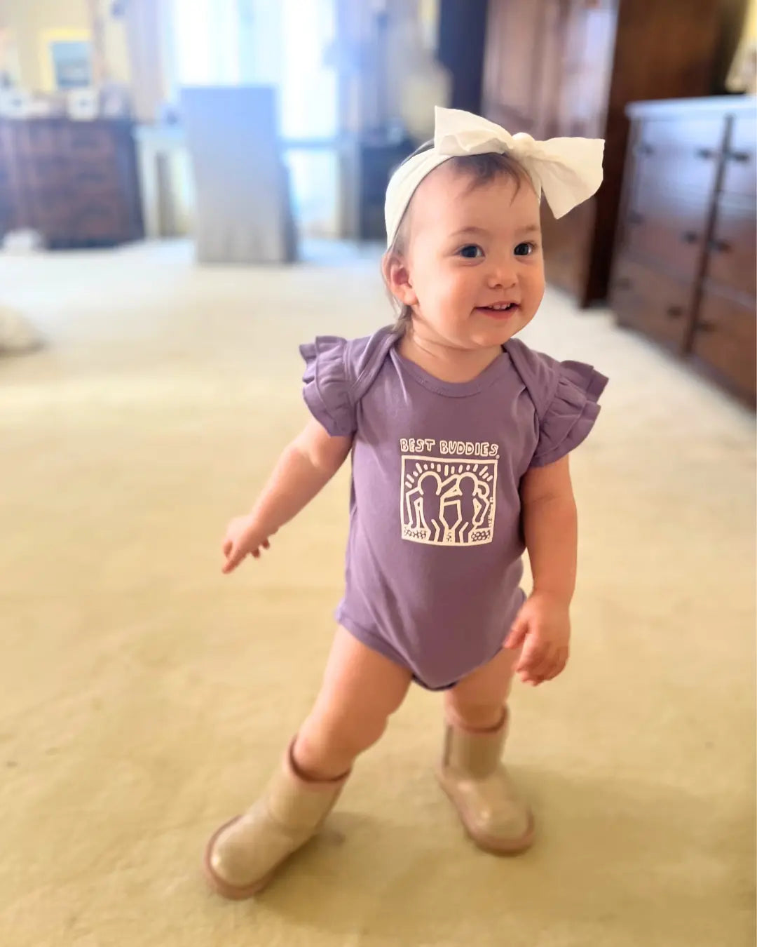 Lavender baby onesie with white haring Best Buddies logo on the front