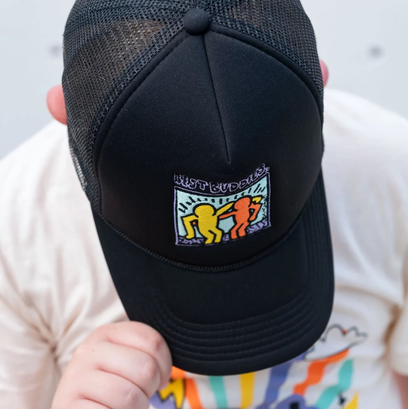 Black trucker hat with colorful traditional haring Best Buddies logo