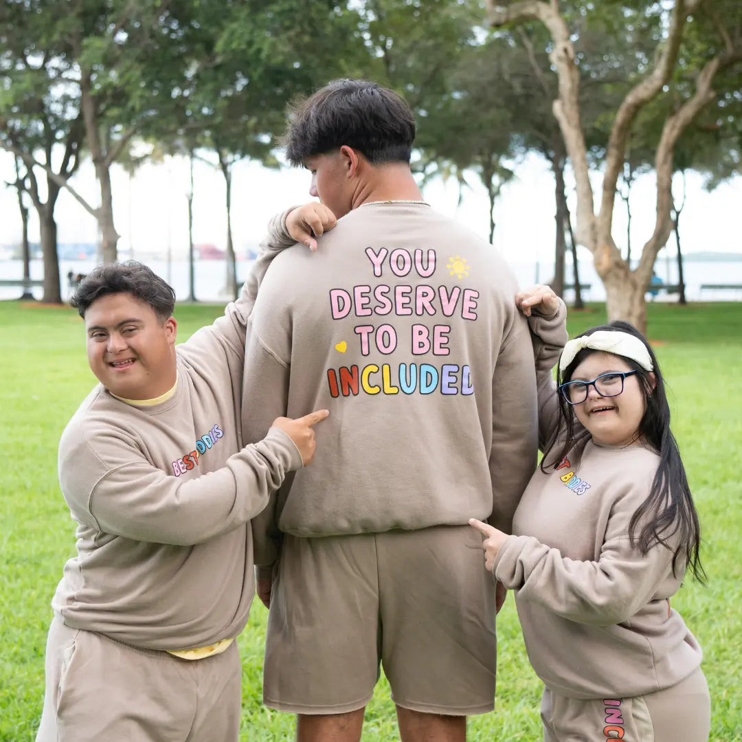 Best Buddies Crewneck beige Sweatshirt with ‘You Deserve to Be Included’ message printed in colorful letters on the back.
