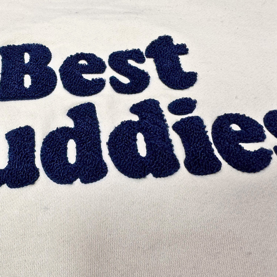 Cream Chenille sweatshirt with navy embroidered "Best Buddies" on the front