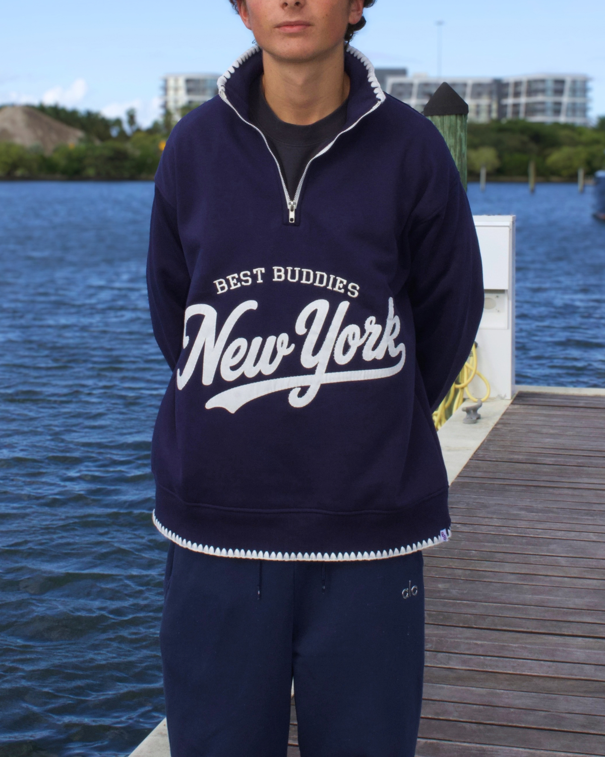 Model wearing a navy blue Best Buddies "New York" quarter-zip sweatshirt, front view.