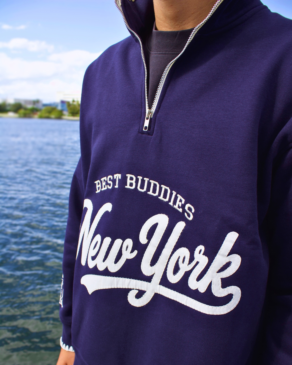 Close-up front view of a navy blue quarter-zip sweatshirt with Best Buddies "New York" across the chest.