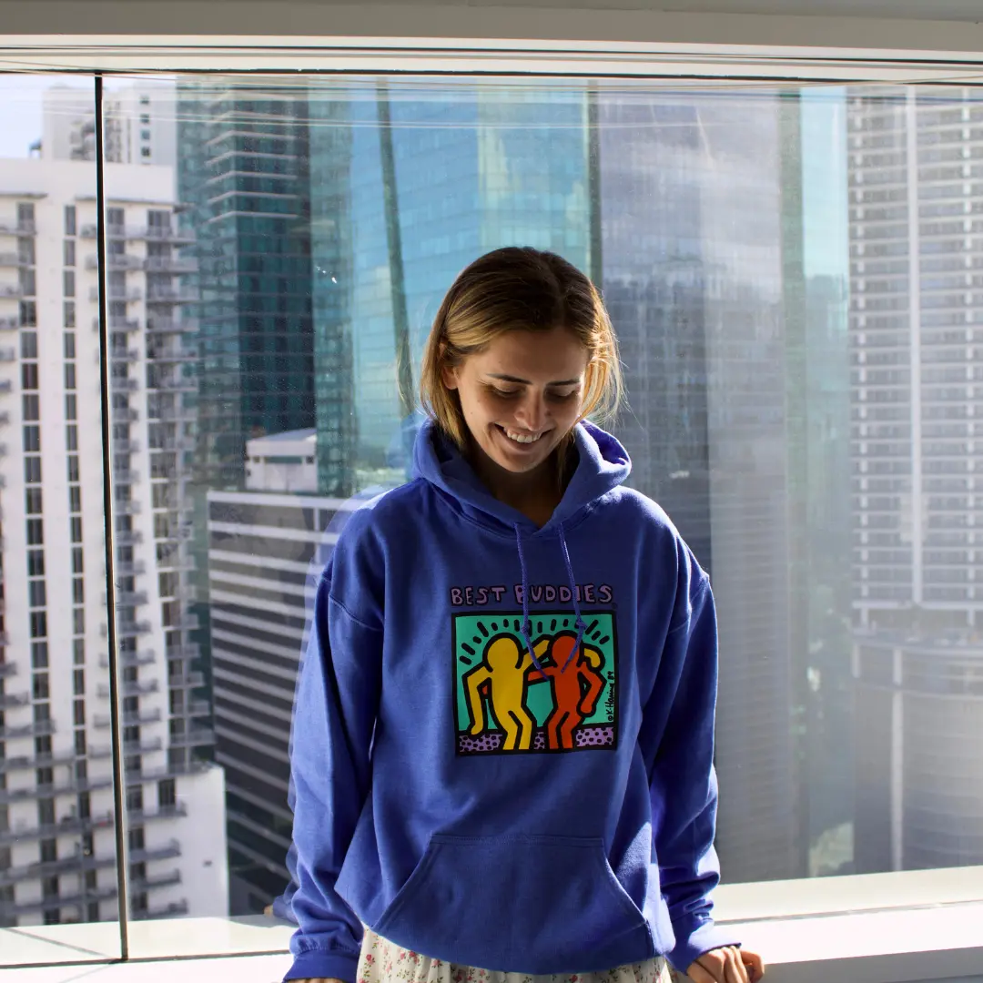 girl sitting at window wearing heather royal hoodie with best buddies logo on front